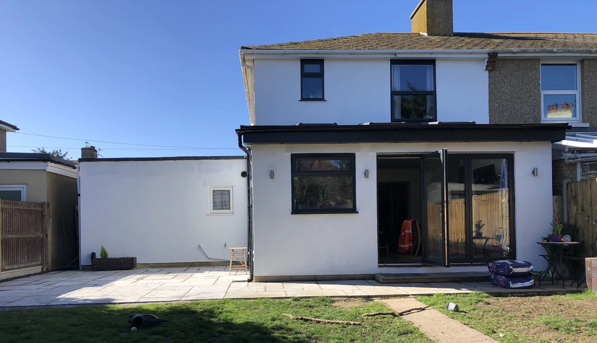 Rear of a house with an extension and glazed doors opening onto a patio