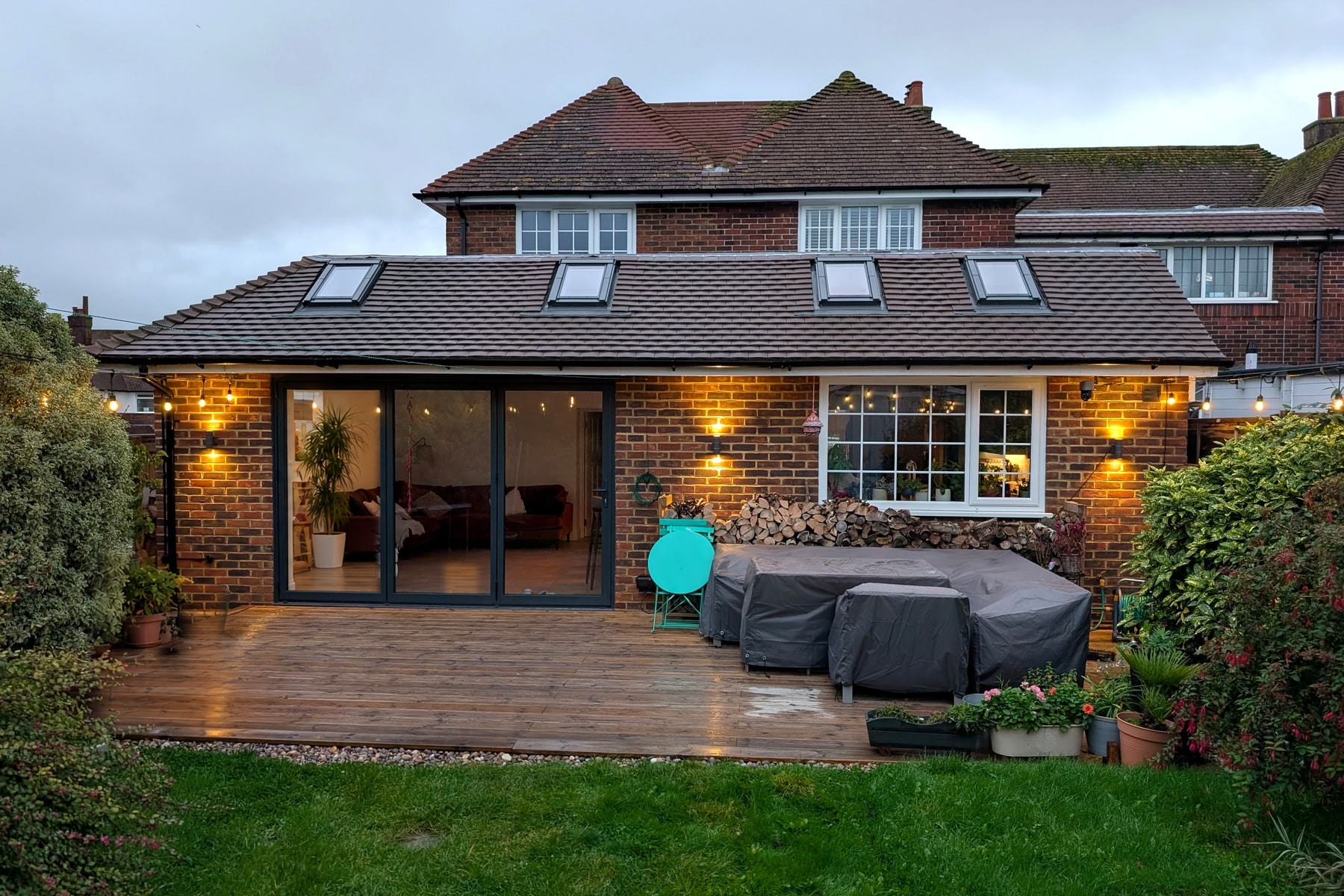 Completed Folkestone wraparound extension with rooflights and glazed doors opening onto a garden deck
