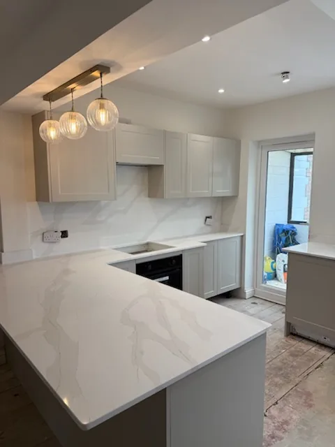 Fitted kitchen cabinets, pale worktops and pendant lights in the Dover kitchen