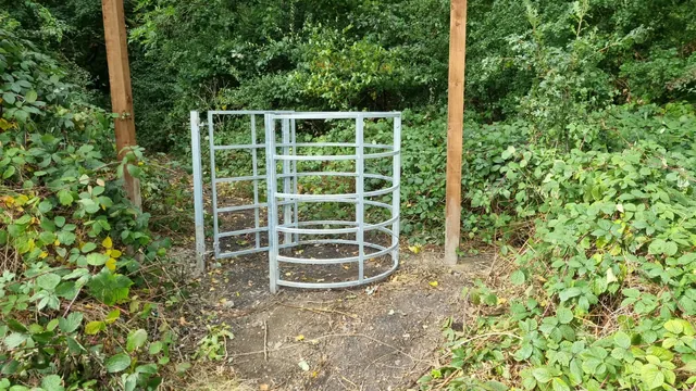 Steel pedestrian gate and curved enclosure on a wooded path