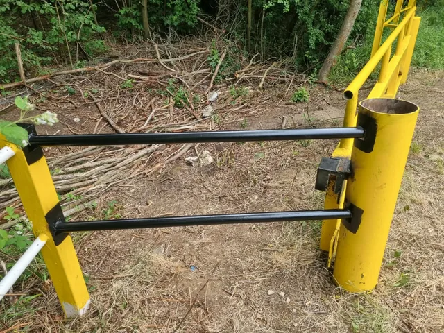 Two steel rails joined to a large yellow post and lock housing