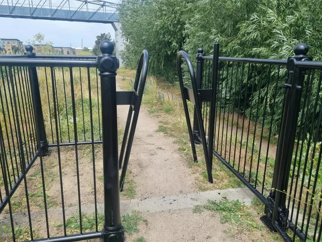 Black steel entrance railings and barriers beside a footpath