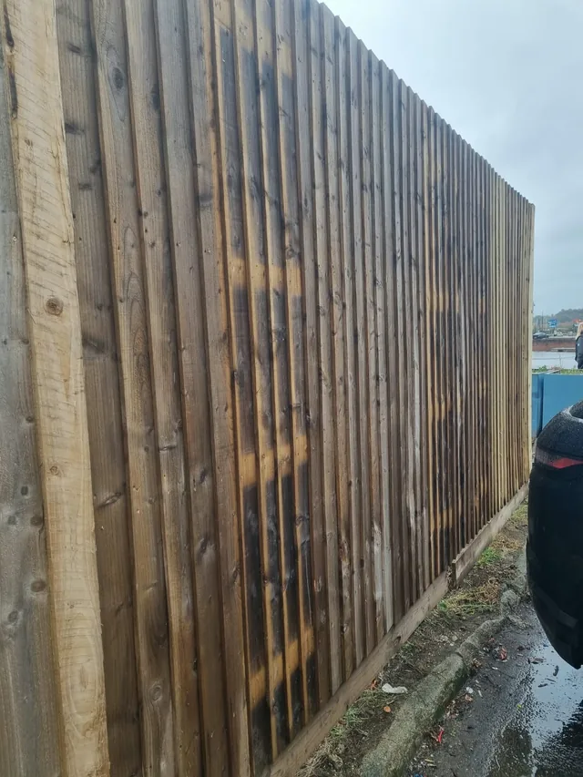 Tall timber board fence beside a paved area