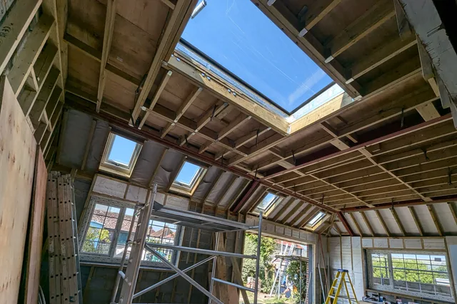 Exposed roof framing and a large rooflight during construction