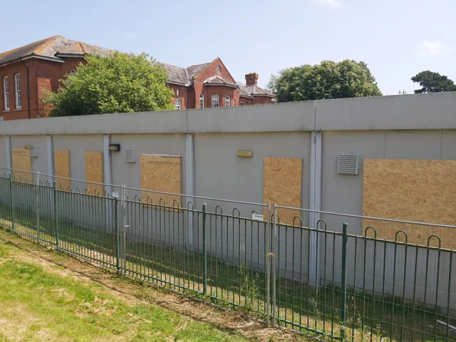 Timber boards securing window openings along a vacant building