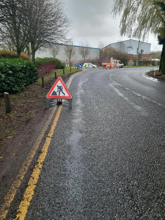 Roadworks warning sign and cones marking a road repair work area