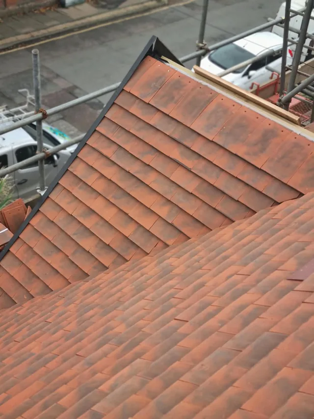 Red roof tiles at a roof junction with scaffolding alongside