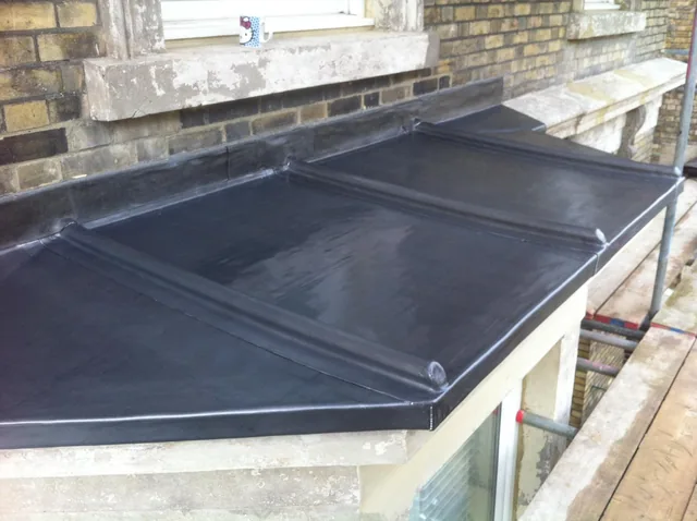 Small bay roof with raised seams against a brick wall