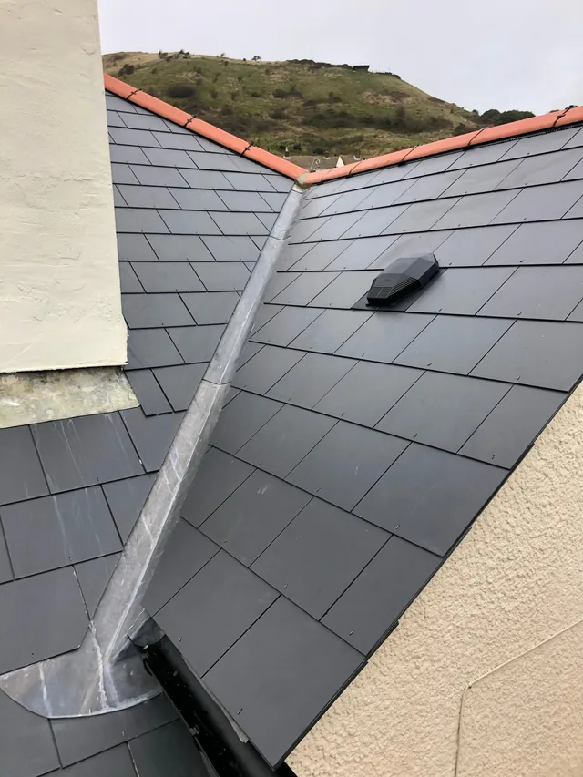 Valley between two tiled roof slopes beside a rendered chimney