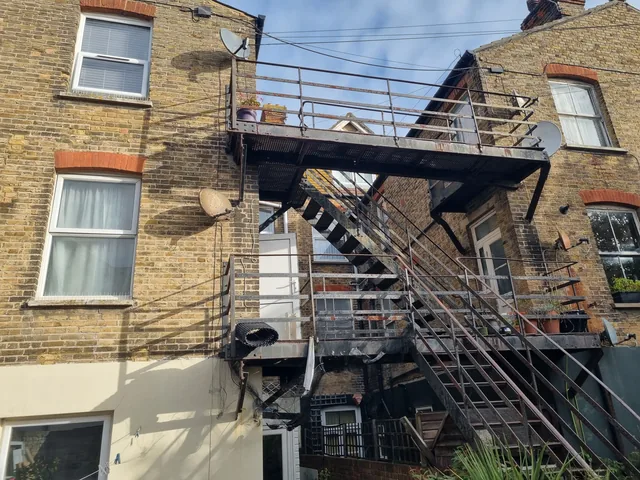 Large external steel staircase and landings beside yellow-brick buildings