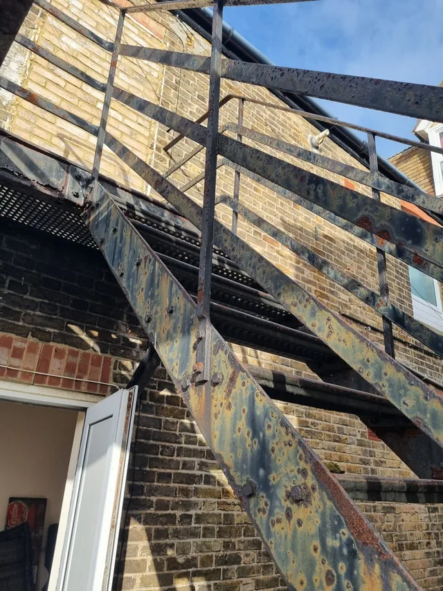 Stair stringer, treads and railings with exposed and corroded steel surfaces