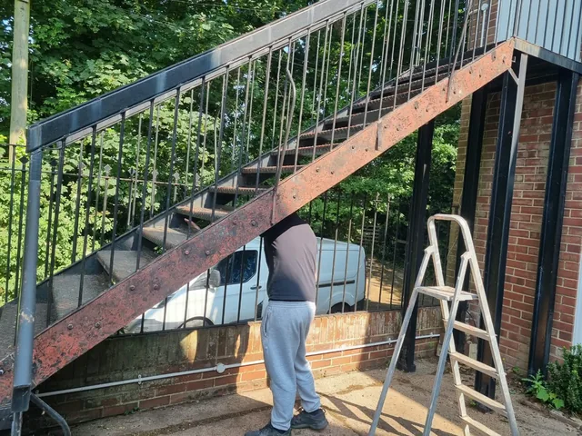 Work on a long external steel staircase with decorative railing details
