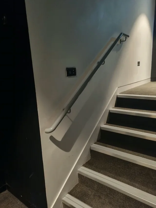 Wall-mounted steel handrail alongside a theatre staircase