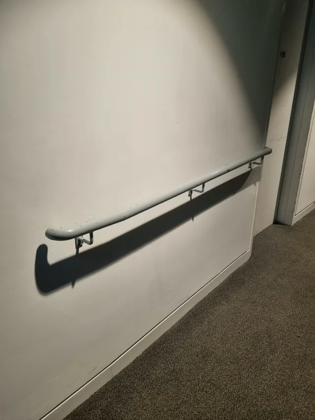 Straight steel handrail fixed to a theatre wall